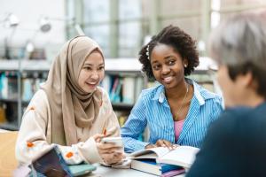 Two feminine-presenting students of Color. One is wearing a hijab.