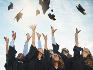 High school students in graduation regalia throwing caps in the air