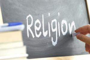 Hand writing "religion" on a chalkboard